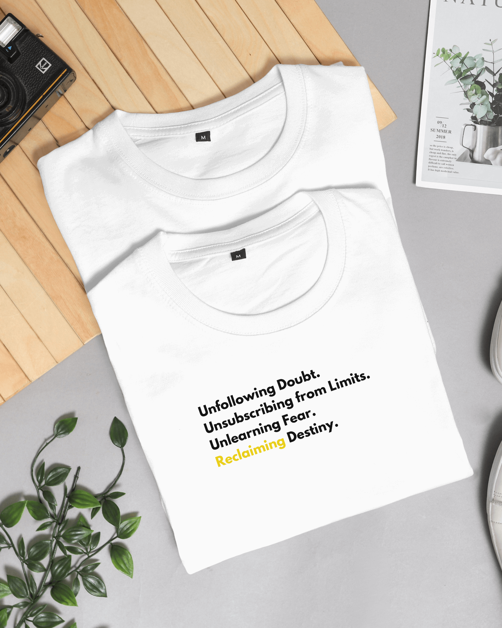 Two white tees with motivational texts in black and Golden color