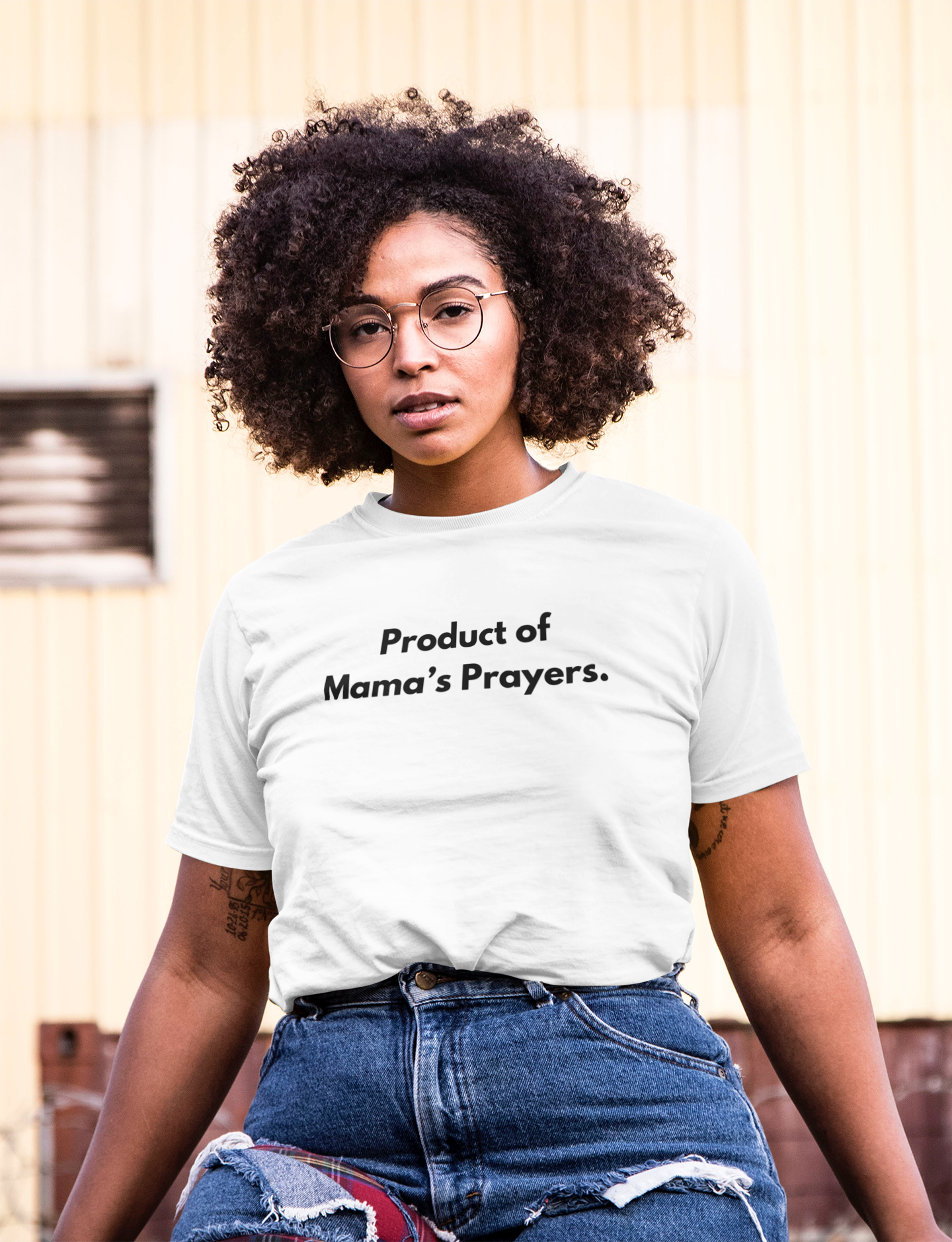 Wome in White tee with text ' Product of Mama's Prayers' and blue jeans