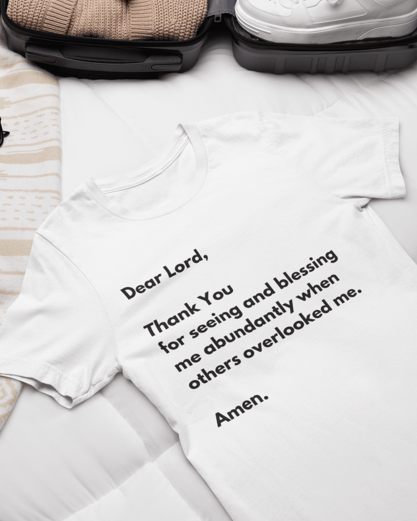 T-shirt with prayer text on bed with suitcase